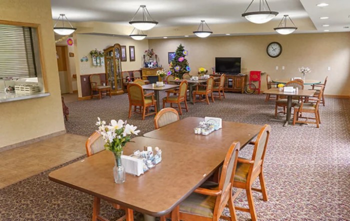 A well-lit dining area with neatly arranged tables and chairs, decorated with flowers.
