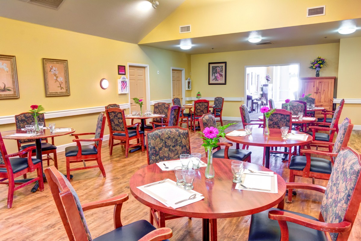 A cozy dining area with neatly arranged tables and chairs, decorated with flowers.