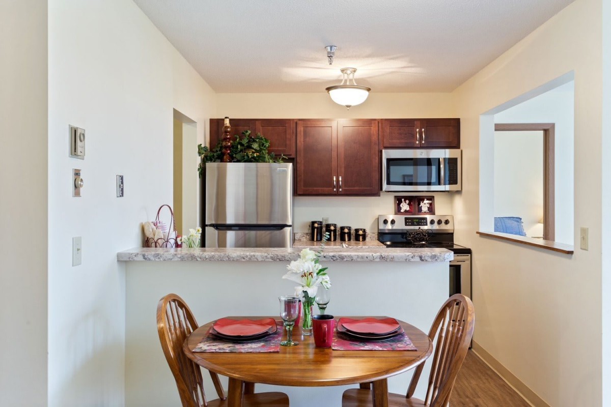A cozy kitchen with a small dining area featuring modern appliances and a wooden table set.