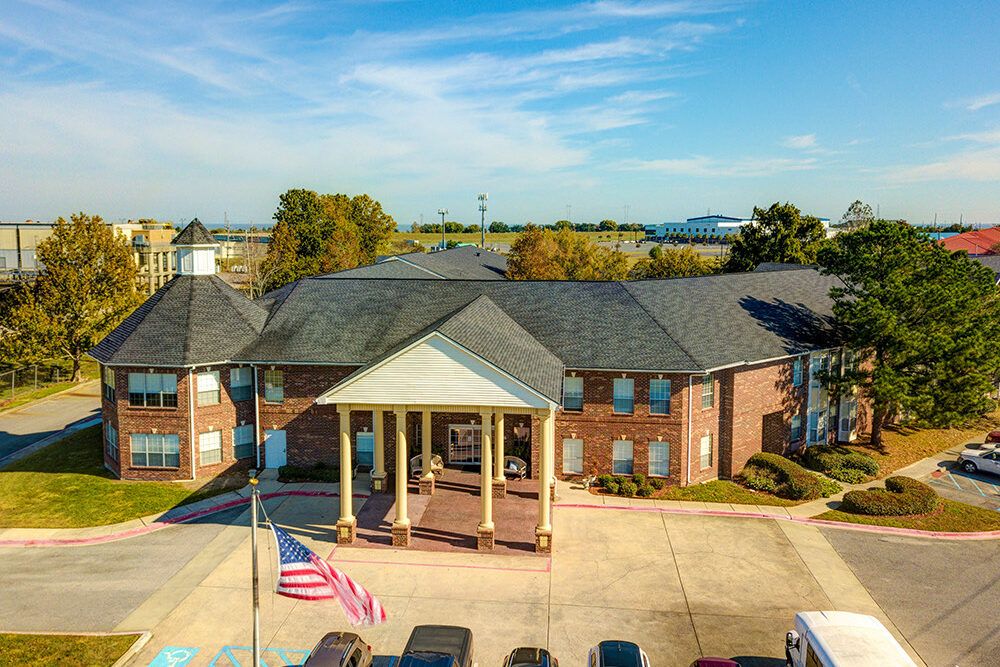 Aerial view of a brick hotel with a prominent entrance and parking area.