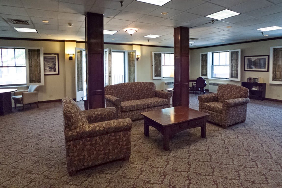 A cozy lobby area featuring comfortable sofas, chairs, and a central table on a carpeted floor.