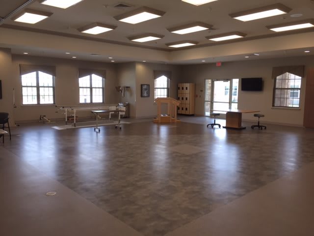 A spacious room with various pieces of furniture and large windows.