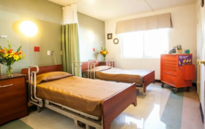 A well-lit hospital room with two beds and medical equipment.
