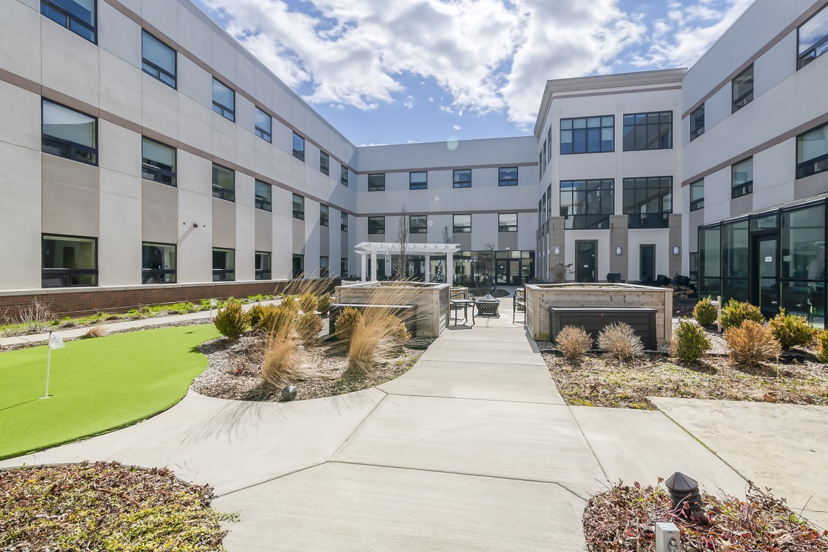 A modern building with a landscaped courtyard featuring pathways and outdoor seating.