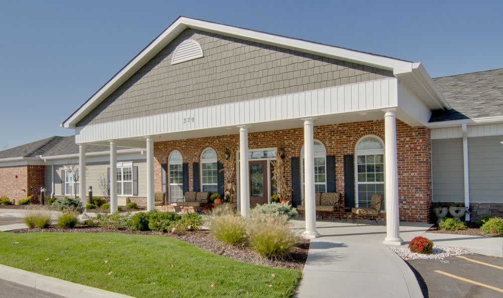 A residential building with a porch and landscaped front yard.