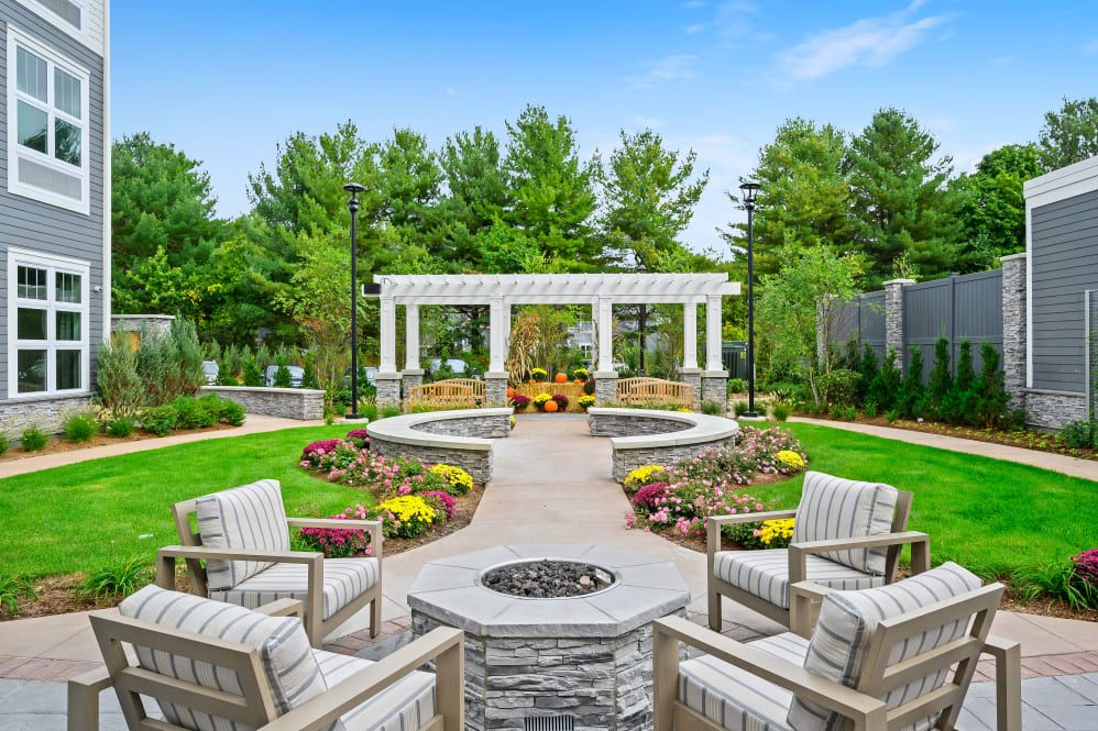 A beautifully landscaped outdoor patio with a fire pit and seating area surrounded by greenery.