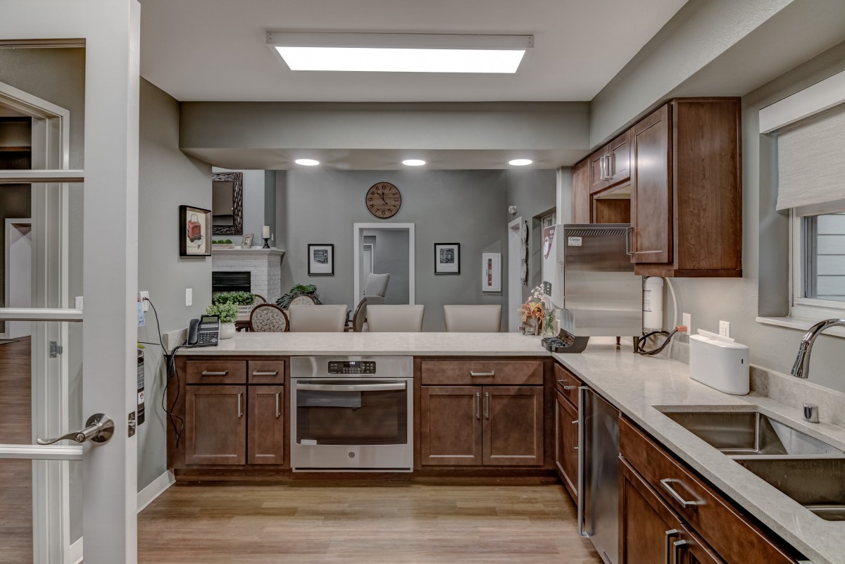 A modern kitchen with brown cabinets, stainless steel appliances, and bar seating.