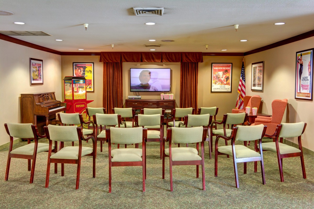 A compact presentation room equipped with chairs and a television for meetings or lectures.