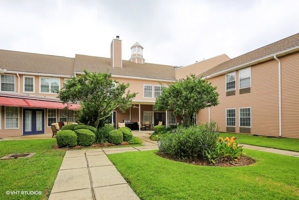 A view of a residential building with a landscaped garden and walkway.