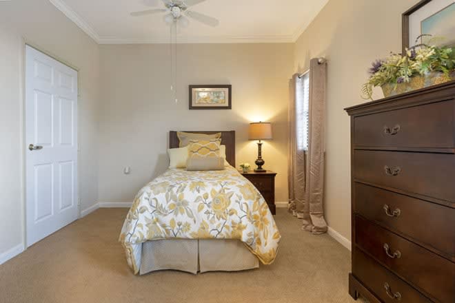 A cozy bedroom with a single bed and warm lighting.