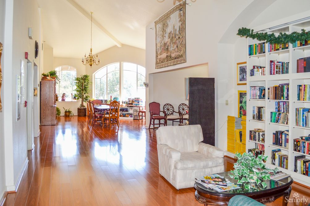 A bright and spacious living room with wooden flooring, featuring a dining area, comfortable seating, and tasteful decor.