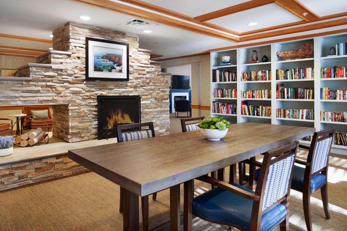A cozy dining room with a wooden table, fireplace, and bookshelves.