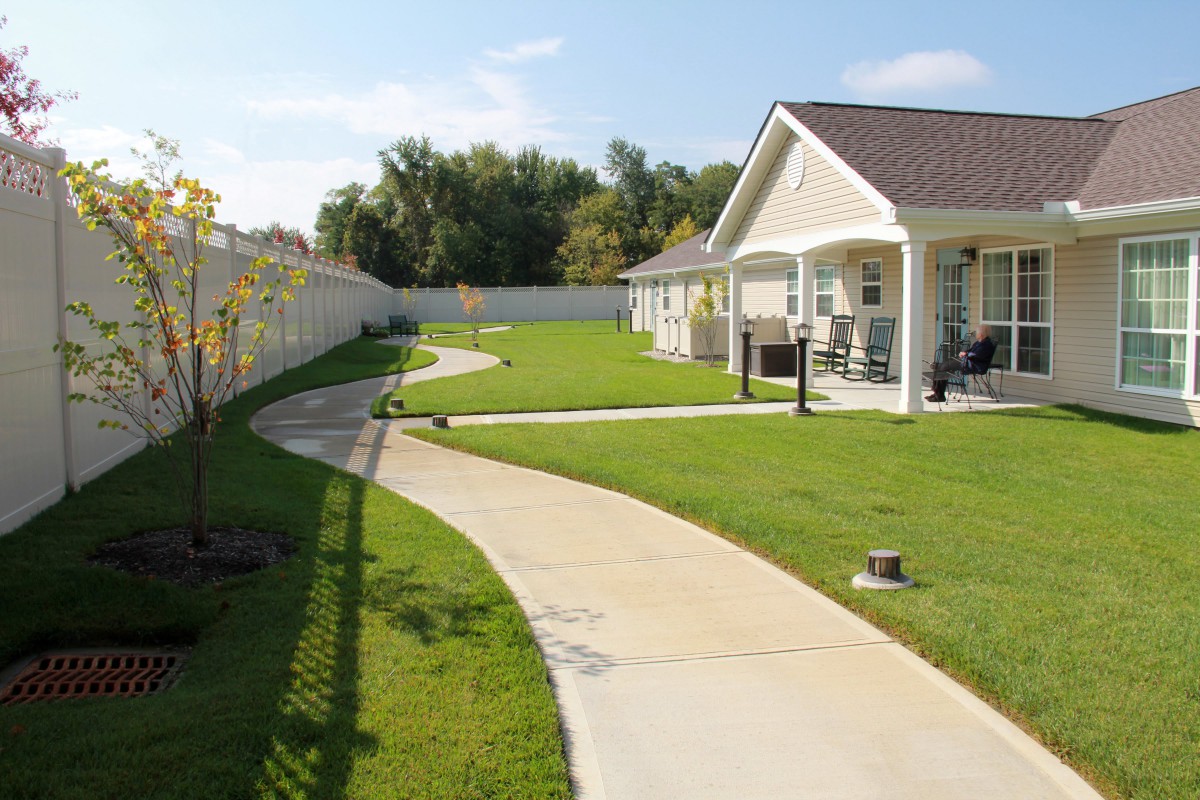 A well-kept suburban backyard with a concrete pathway leading to a house.