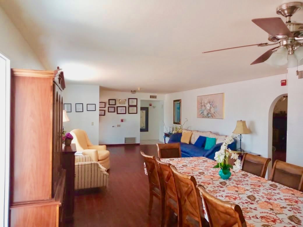 A cozy living room with a dining area, featuring a sofa, chairs, and wall art.