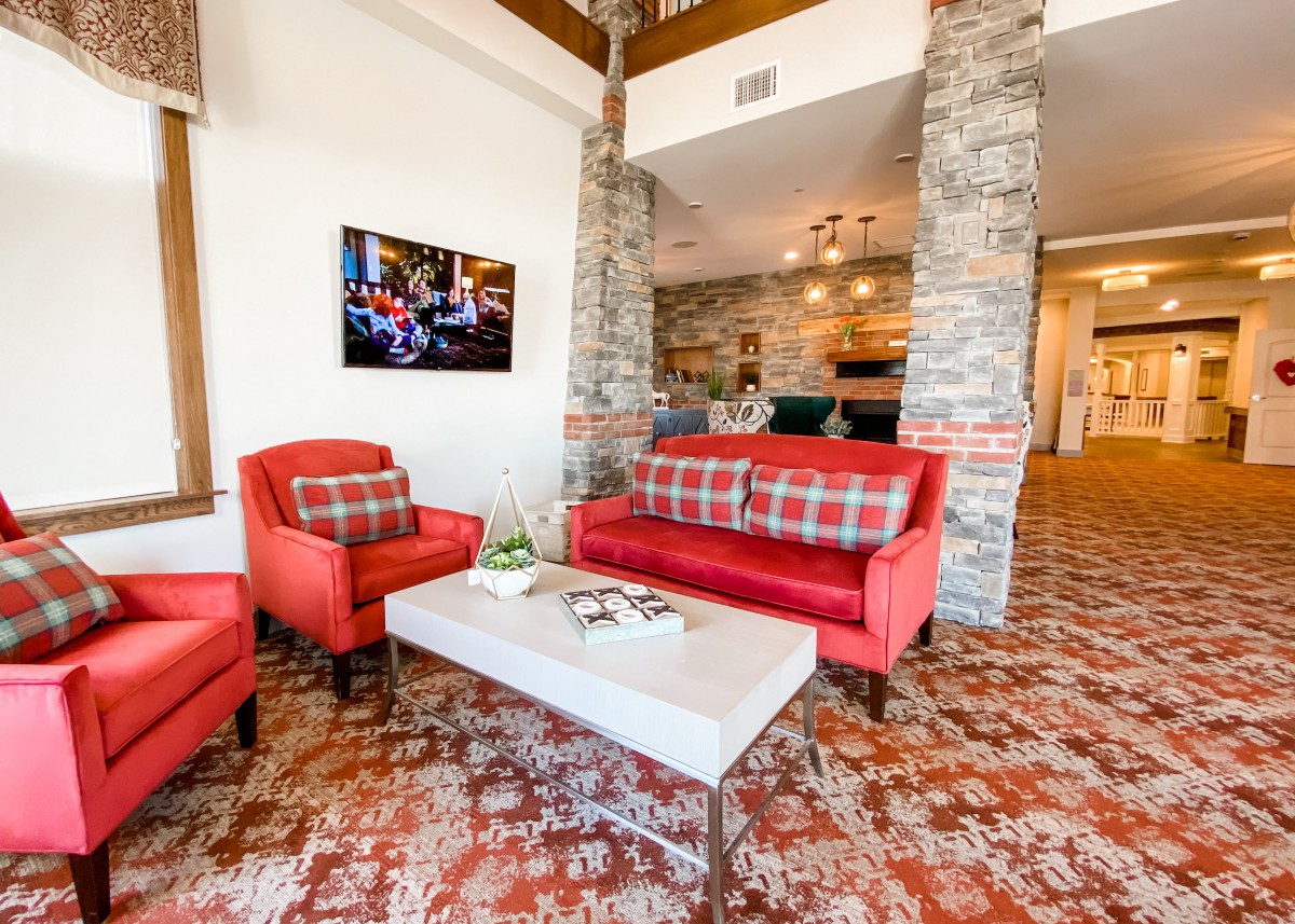 A cozy living room with red furniture and stone walls, featuring modern decor.