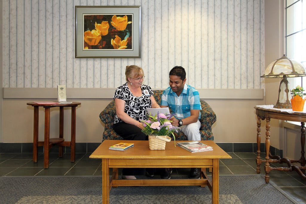 Two people sitting in a waiting room, engaging in conversation while looking at documents.