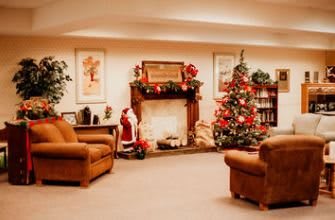 A cozy living room decorated for Christmas with a beautifully adorned tree and festive fireplace.