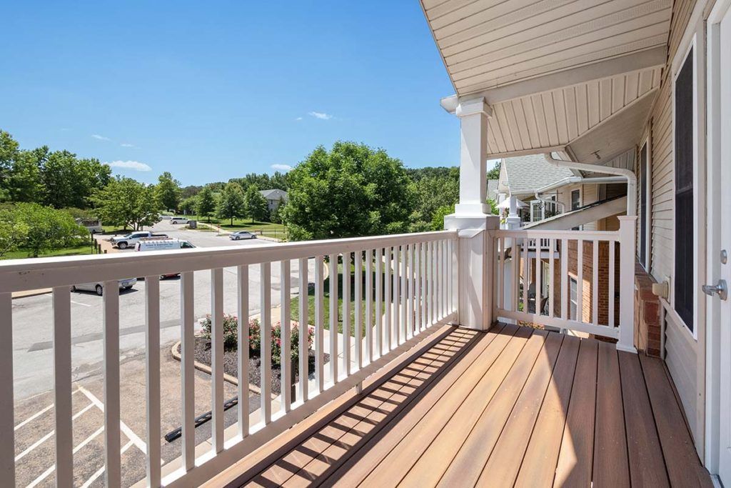 A sunny suburban balcony overlooking a residential street with trees.