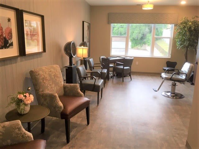 A cozy waiting area in a hair salon with comfortable chairs and a large window.
