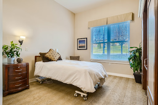A serene bedroom setting featuring a neatly made bed, warm lighting, and a view of nature through the window.