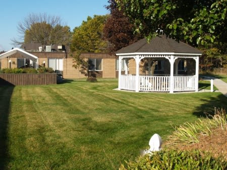 A well-maintained lawn with a white gazebo and house in the background.