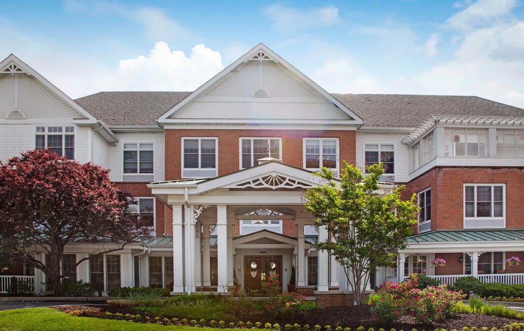 A large residential building with columns and landscaped surroundings under a blue sky.