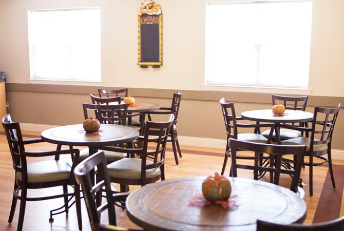 A cozy cafe interior with wooden tables and chairs, adorned with small pumpkins as table decorations.