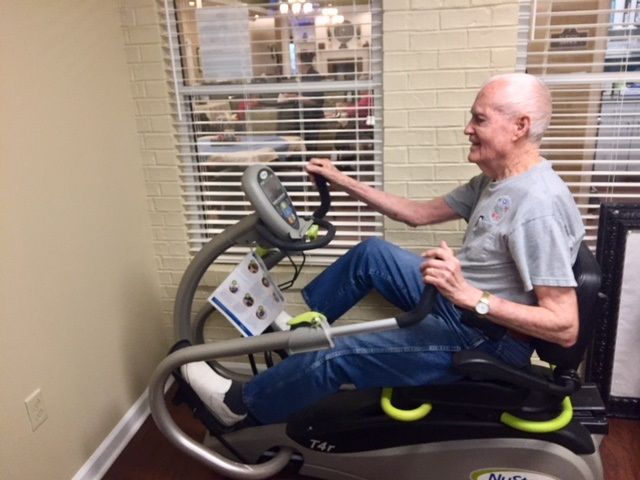 A senior man happily using a fitness machine indoors.
