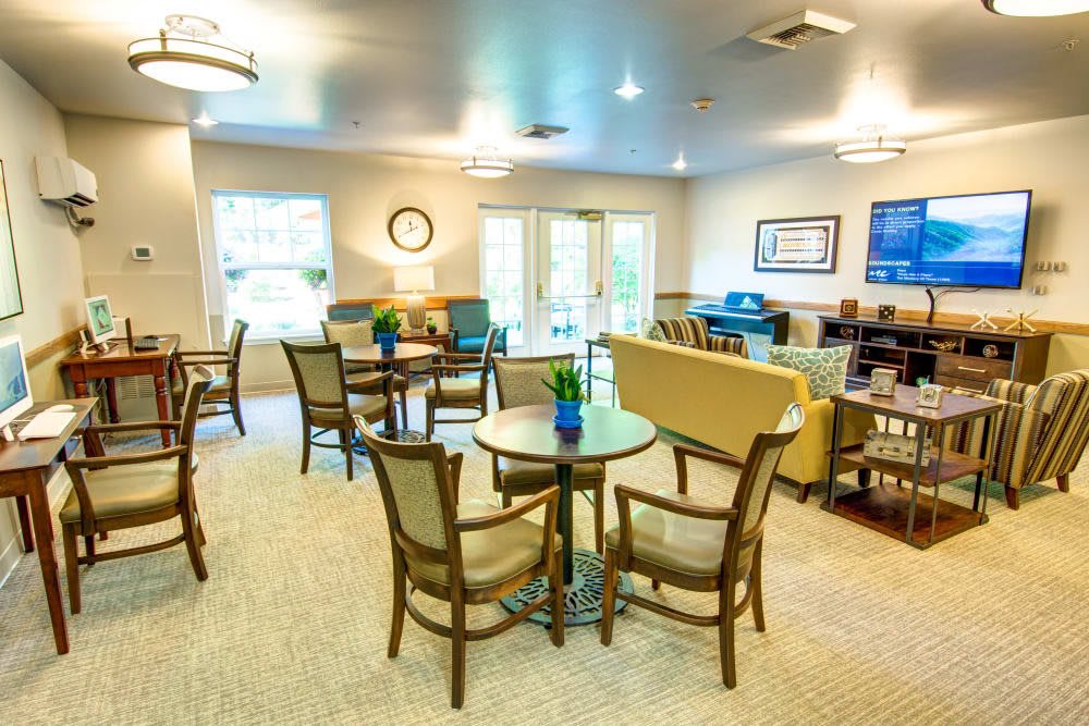A bright and cozy living room with several tables and chairs arranged for social gatherings.