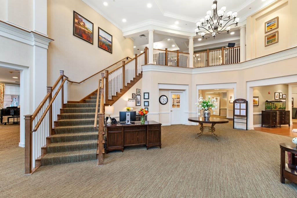 A spacious lobby area featuring a grand staircase and elegant chandelier.