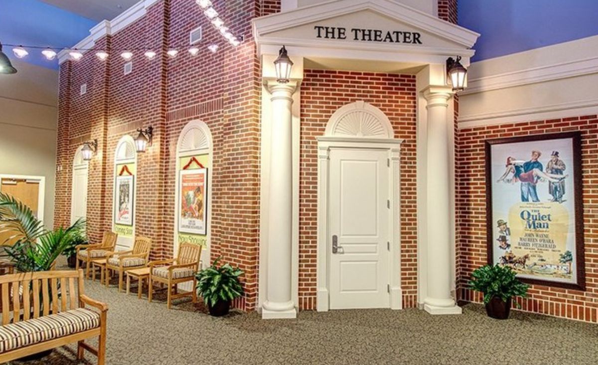 Entrance to a theater with brick walls, illuminated by string lights and decorated with posters.