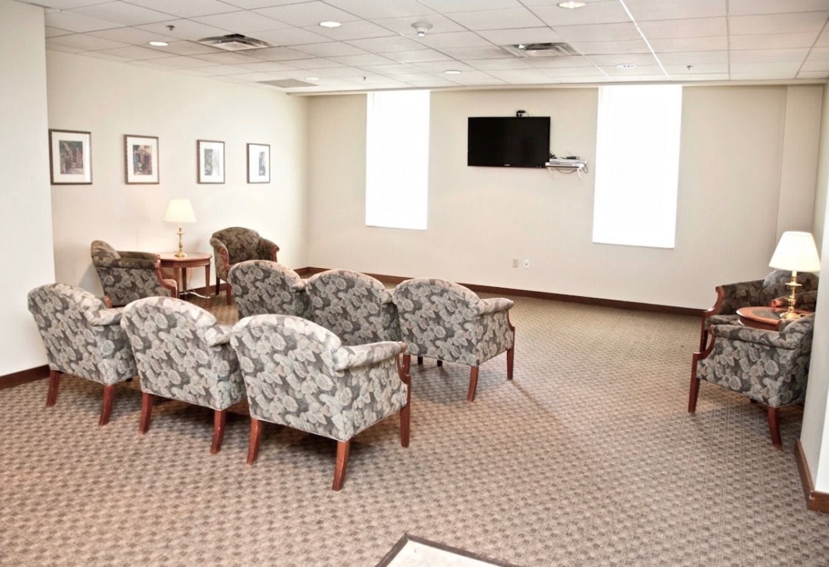 A well-lit waiting room with patterned chairs and a wall-mounted television.