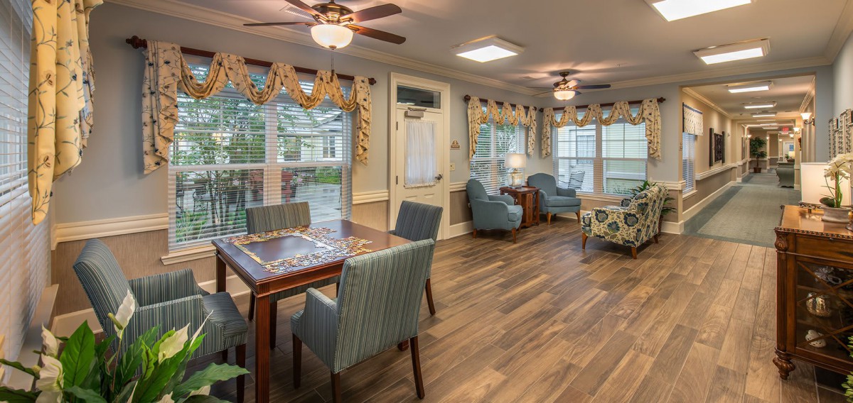 A cozy living room with wooden flooring, ceiling fans, and comfortable seating.