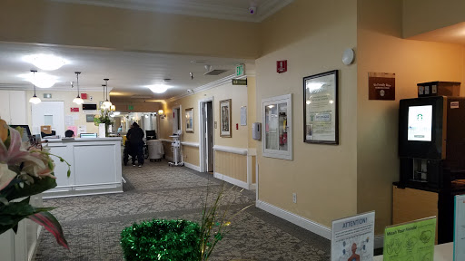 A well-lit hallway with decorative artwork and greenery, leading to various rooms.