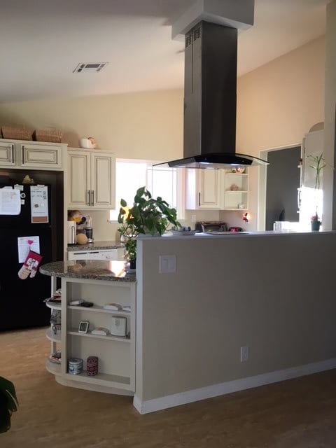 A cozy kitchen with a central island, surrounded by cabinets and appliances.