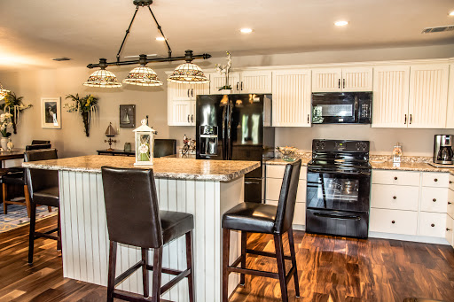 A stylish modern kitchen featuring sleek black appliances, elegant bar stools, and a beautiful granite countertop.