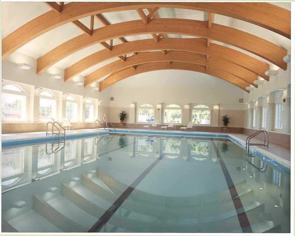 A spacious indoor swimming pool with wooden beams and large windows.