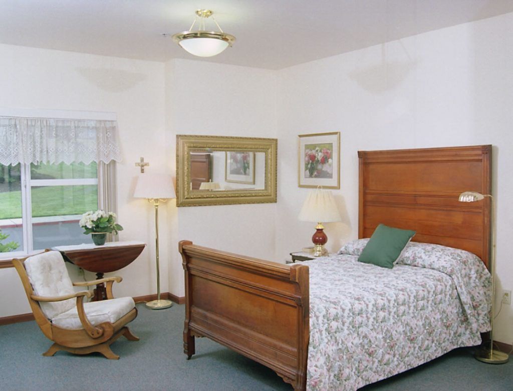 A cozy bedroom featuring a wooden bed, a decorative lamp, and a comfortable chair by the window.