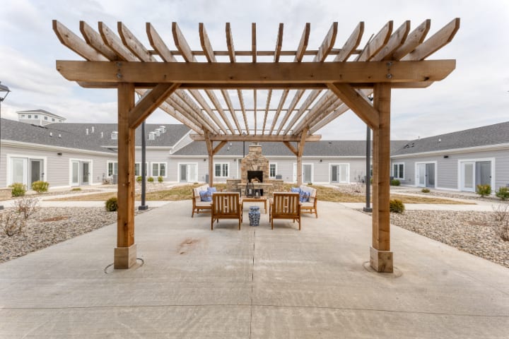 A well-designed outdoor courtyard features a wooden pergola with comfortable seating and a fireplace.