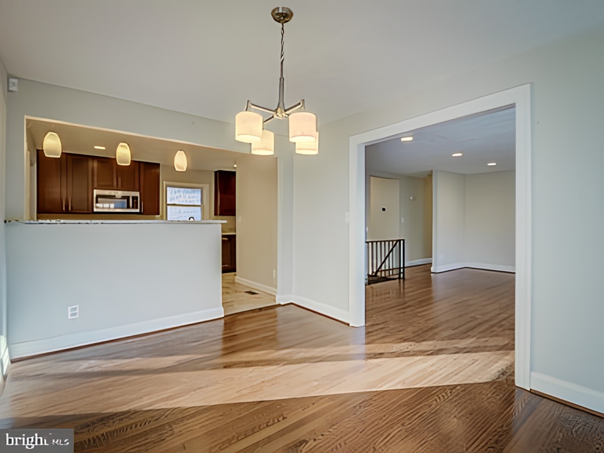 A spacious open floor plan with a view of the kitchen and living area, featuring hardwood floors and modern lighting.