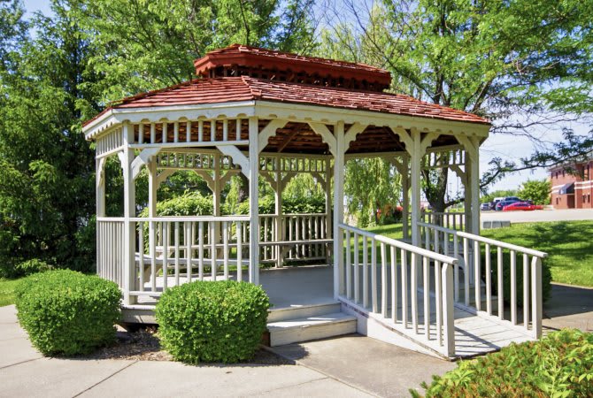 A charming wooden gazebo in a lush garden setting.