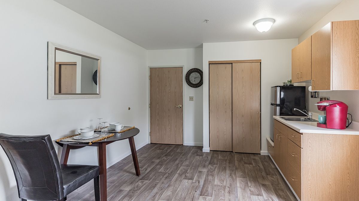 A minimalist room with a small table, mirror on the wall, and wooden flooring.