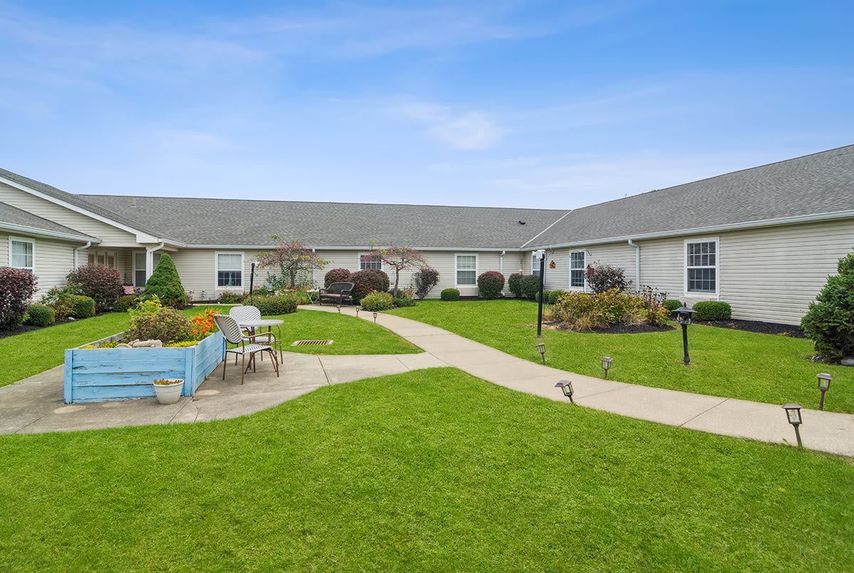 A well-maintained building with a green lawn and garden, featuring outdoor seating and a pathway.