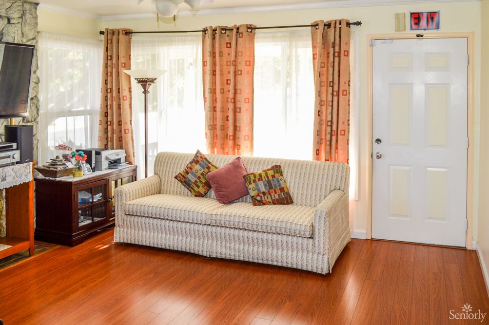 A cozy living room with a striped sofa, decorative pillows, and warm-toned curtains.