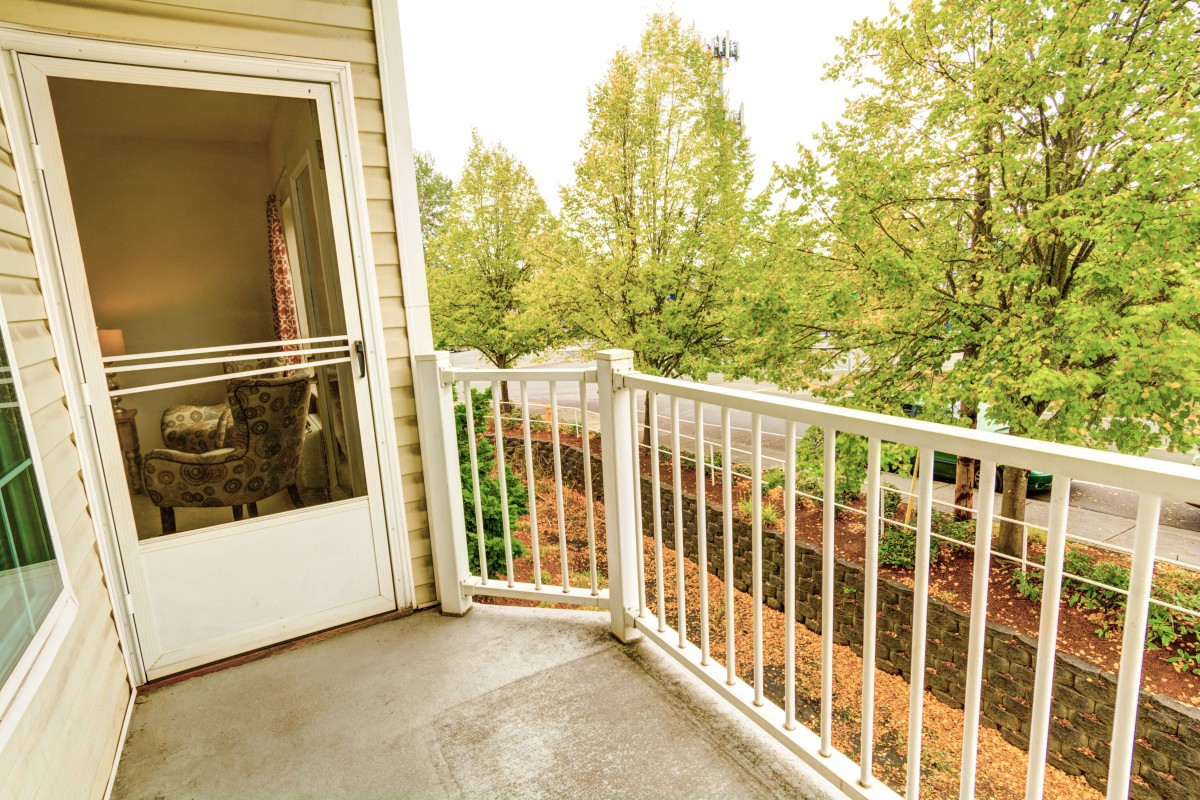 A cozy balcony with a view of lush green trees.