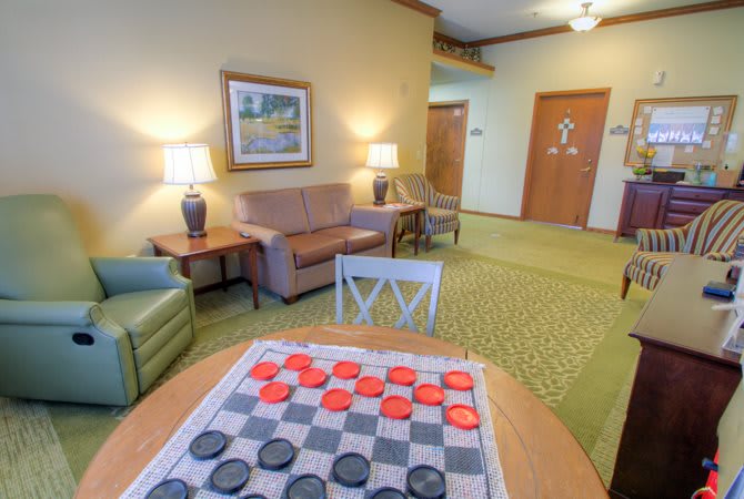 A cozy lounge area featuring a checkers game setup, sofas, and soft lighting.