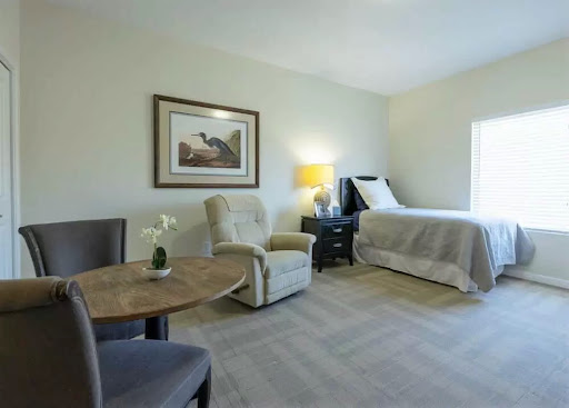 Cozy and well-lit room featuring a bed, seating area, and tasteful decor.
