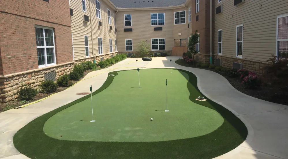 A well-maintained putting green located in the courtyard of an apartment complex.