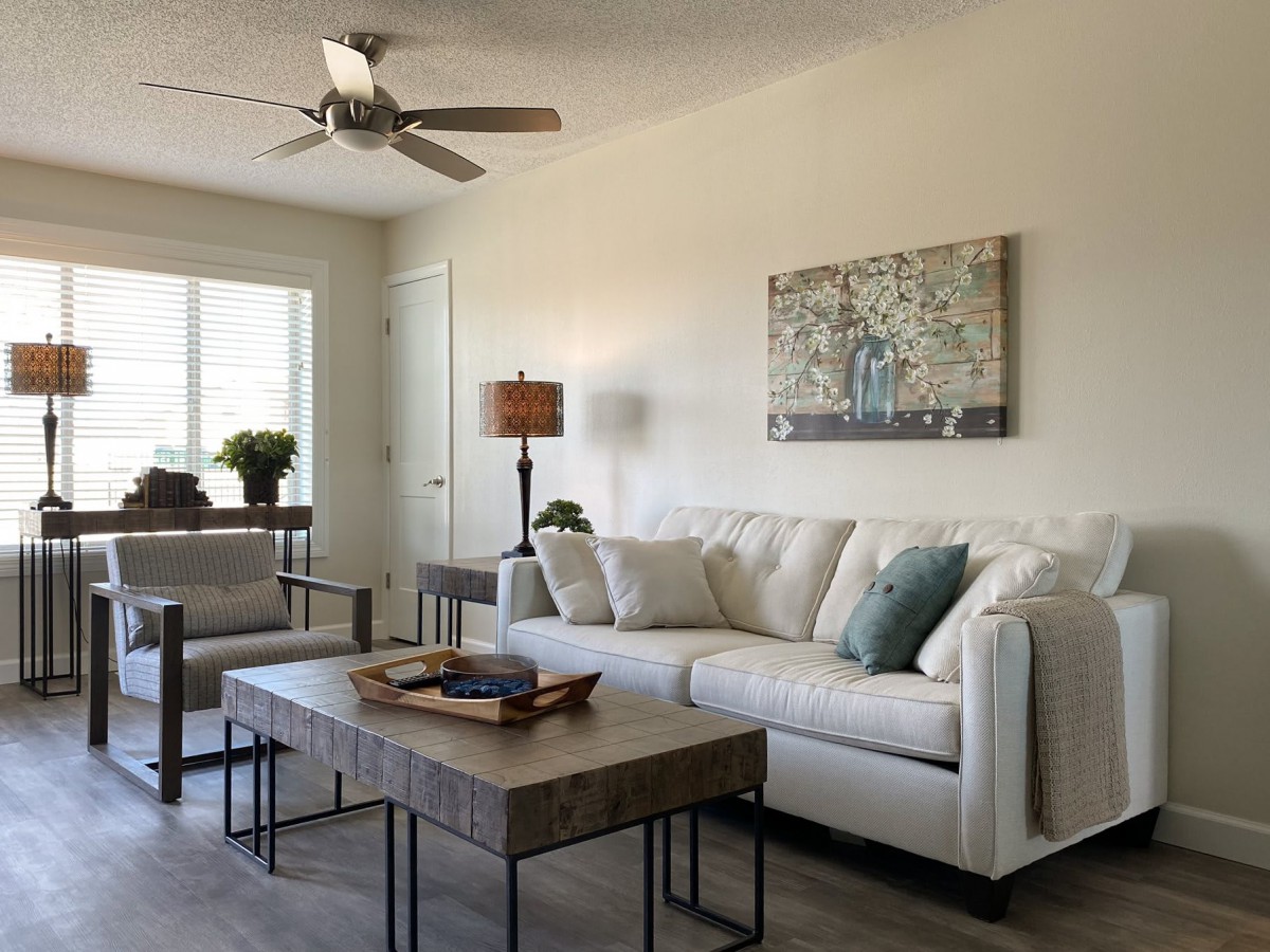 A modern living room with a comfortable white sofa, wooden coffee table, and decorative artwork on the wall.