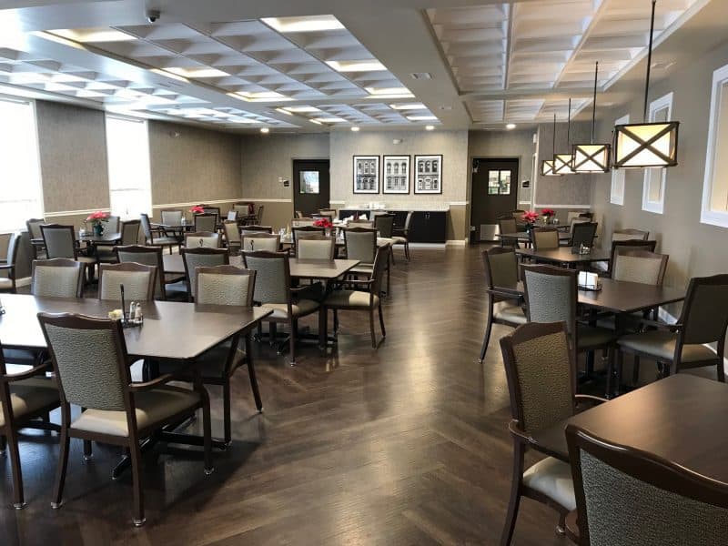 A spacious dining area with neatly arranged tables and chairs, featuring modern interior design and lighting.